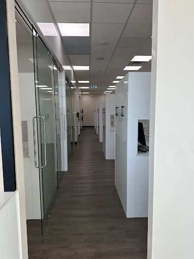 The bright glass-doored hallway connecting the operatories at Orchards Smiles Dental