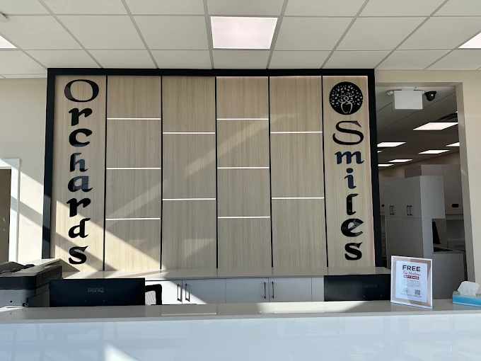 The Orchards Smiles Dental front desk, with the branded wood feature wall behind reception
